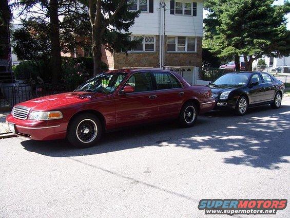 Red sedan parked on street, black sedan behind it