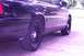 1999 Ford Crown Victoria - The side of a dark-colored sedan is shown, focusing on the rear wheel and fender area.