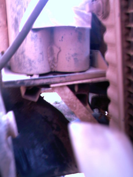 Engine bay with two cylindrical components, metal brackets, and part of a radiator