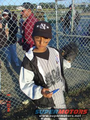 kid in baseball uniform with glove and hat