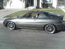 Gray 1990s coupe, side view, aftermarket wheels