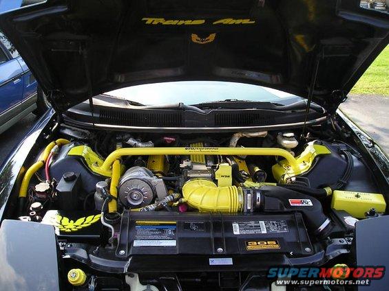 Engine bay of a 1994 Pontiac Trans Am with yellow accents and a strut bar