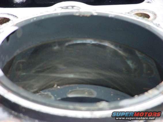 Engine cylinder with visible scoring and residue inside. Watermark reads SUPERMOTORS