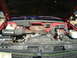 1990 Chevrolet C/K Pickup - The engine bay of a red 1990 Chevrolet C/K Pickup is visible with the hood raised, revealing the V8 engine and associated components.