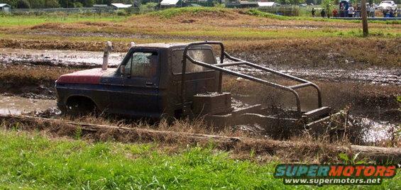 Modified pickup truck with roll cage stuck in mud, exhaust pipe sticking straight up