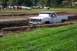 1979 Ford Bronco - A white pickup truck is stuck in a muddy track with spectators in the background.