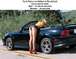 1999 Ford Crown Victoria - Black convertible sports car with a woman leaning into the passenger side.