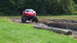 1979 Ford Bronco - A modified red car on massive tires navigates a challenging mud course.