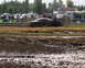 1979 Ford Bronco - A vehicle is stuck in a mud pit during an event, with onlookers in the background.