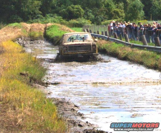 Yellow 1979 Ford Bronco driving through mud