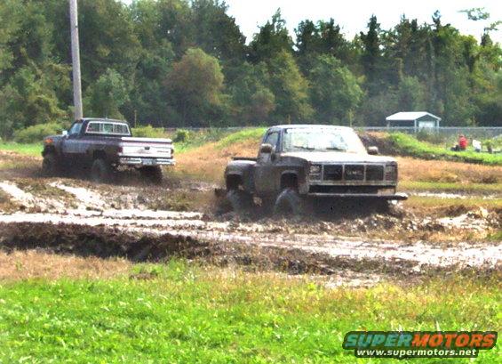 Front view of a GMC pickup truck in mud, with another truck behind