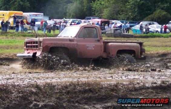 Red pickup truck stuck in mud, with "HADDOCK AUTO CENTER" on the door