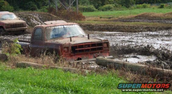 Two trucks stuck in mud, one with 'HARD BOGGER' on windshield
