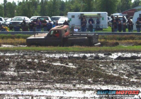 Mud-covered pickup truck stuck in a mud pit, side view