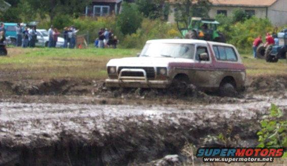 Ford Bronco stuck in mud pit with people watching in background