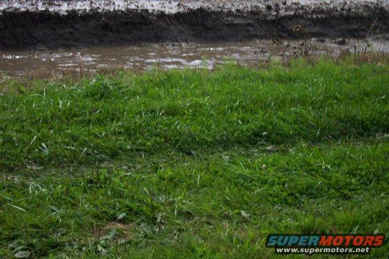 muddy track with grass in foreground, supermotors.net logo in corner