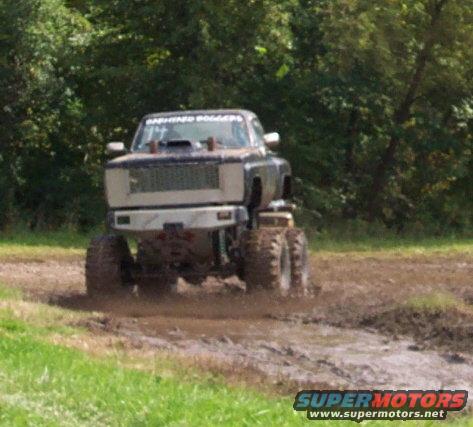 Monster truck with large tires driving through mud. Text on windshield reads 'DASHING DOGERS'