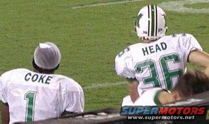 Two football players in uniform on a green field, one with 'COKE 1' on his jersey, the other with 'HEAD 36'