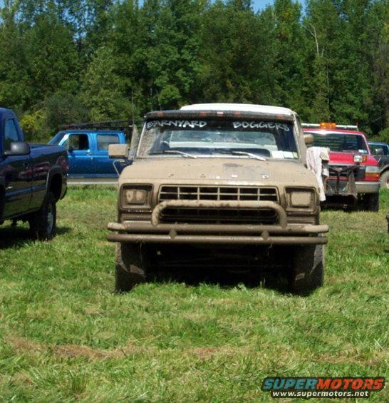 Tan pickup truck with brush guard, mud-splattered, and "BARNYARD BOGGERS" text on windshield