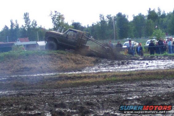 Muddy truck side view, tires deep in mud
