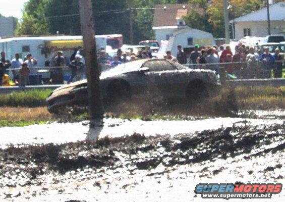 Car stuck in a mud pit with spectators watching
