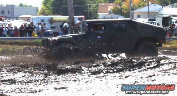 Dark SUV splashing through mud, side view