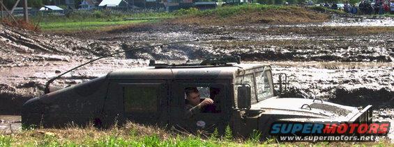 Dark green Humvee stuck in mud, driver visible