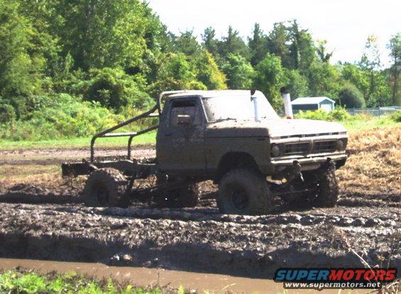 Muddy pickup truck with roll cage stuck in a mud pit