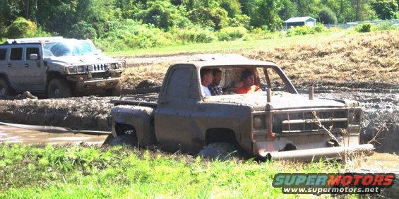 Two trucks stuck in a mud pit, one is a Hummer H2, the other is an older pickup truck