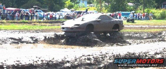 Mud-covered car stuck in mud pit