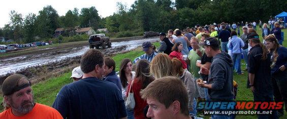 Mud bog event with spectators gathered on the grass and a vehicle driving through mud