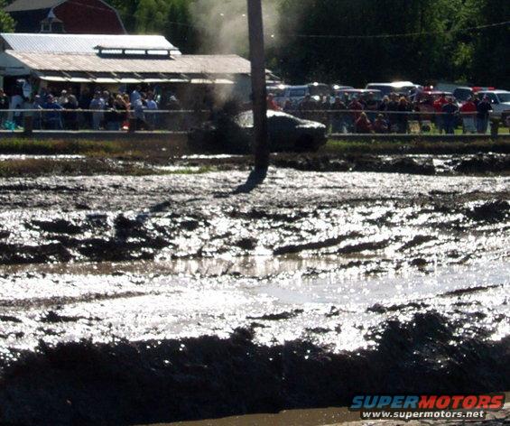 Mud bogging scene with a vehicle emitting smoke