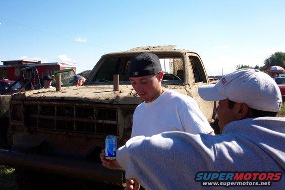 Mud-covered truck with people around it. Supermotors.net logo visible