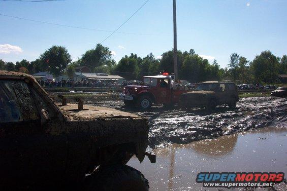 Muddy vehicles in a mud bog with spectators watching