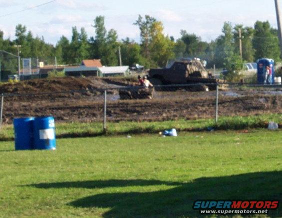 Mud bogging event with a modified truck and a portable toilet in the background