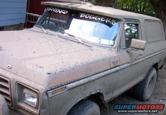 Mud-covered 1978 Ford Bronco, 3/4 front view, showing damage and text on windshield