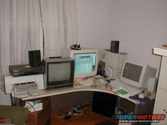 Cluttered desk with computers, VCR, and speakers