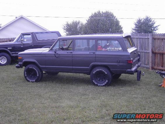 Dark gray 1977 Jeep Wagoneer parked on grass, side view, with rear tailgate open