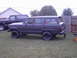 1977 Jeep Wagoneer - A dark gray 1977 Jeep Wagoneer is parked on a grassy lawn next to a dark SUV.