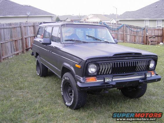 Black 1977 Jeep Wagoneer parked on grass in a backyard