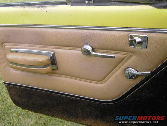 Close-up of a car's tan door panel with chrome handles and window crank. Yellow paint visible at the top