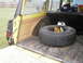 1977 Jeep Wagoneer - The cargo area of a yellow 1977 Jeep Wagoneer contains a spare tire, bottles of fluid, and spray cans.