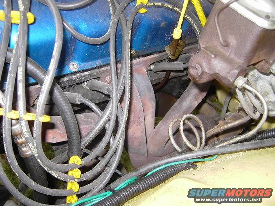 Engine bay detail showing spark plug wires, exhaust manifold, and brake master cylinder