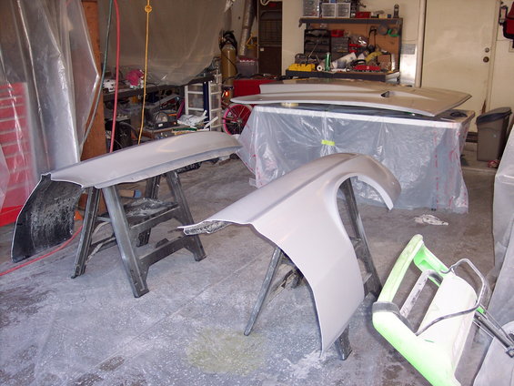 Car fender and hood support on sawhorses in a garage with tools in background