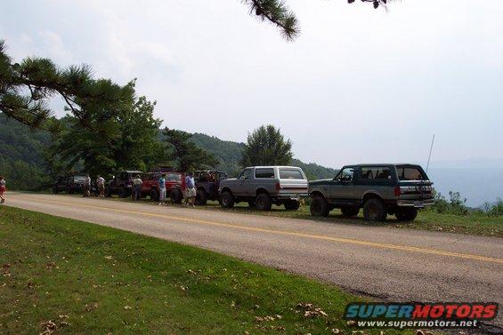 Several Ford Broncos parked on the side of a road with a scenic overlook
