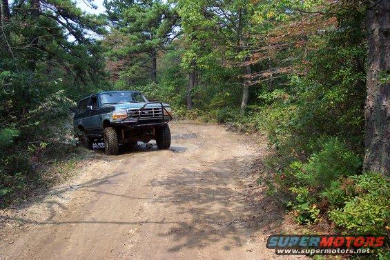 Dark blue Ford Bronco with a brush guard on a dirt road
