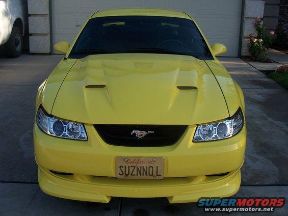 Yellow 2002 Ford Mustang with California plates parked in front of a garage