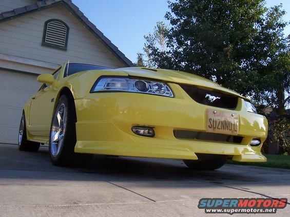 Yellow 2002 Ford Mustang parked in driveway, front view. License plate reads SUZNNOL