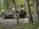 1988 Ford Bronco - A heavily muddied truck is stuck off-road, with trees surrounding it.