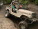 1988 Ford Bronco - A muddy Jeep Wrangler navigates an off-road trail, showing its capabilities.